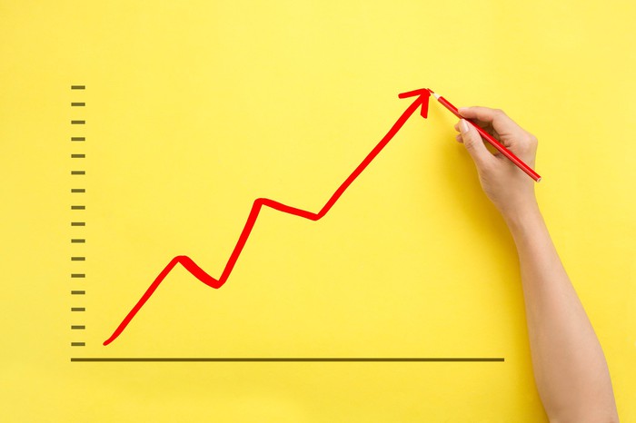 Grafico azionario rosso in aumento disegnato su carta gialla.